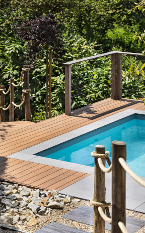 Petite piscine design entourée d’une terrasse en bois exotique et rambarde en corde, réalisée par Nymfeo.