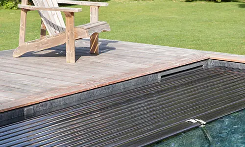 Piscine équipée d’une couverture automatique immergée et entourée d’une terrasse en bois, projet Nymfeo