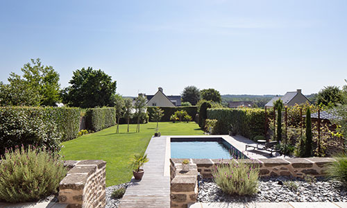 Piscine rectangulaire par Nymfeo dans un grand jardin clos au cœur d’un village breton.